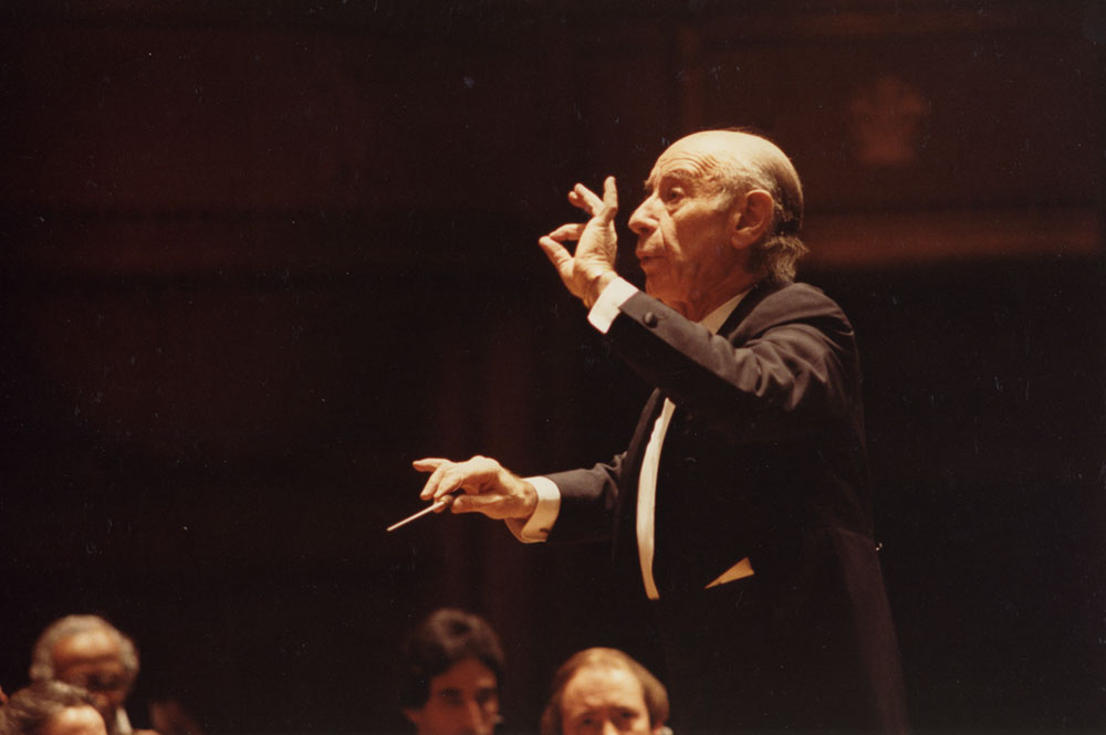 Leinsdorf guest conducting the Orchestra. He is making a gesture with his left thumb and forefinger to emphasize the tapering of a musical phrase. 