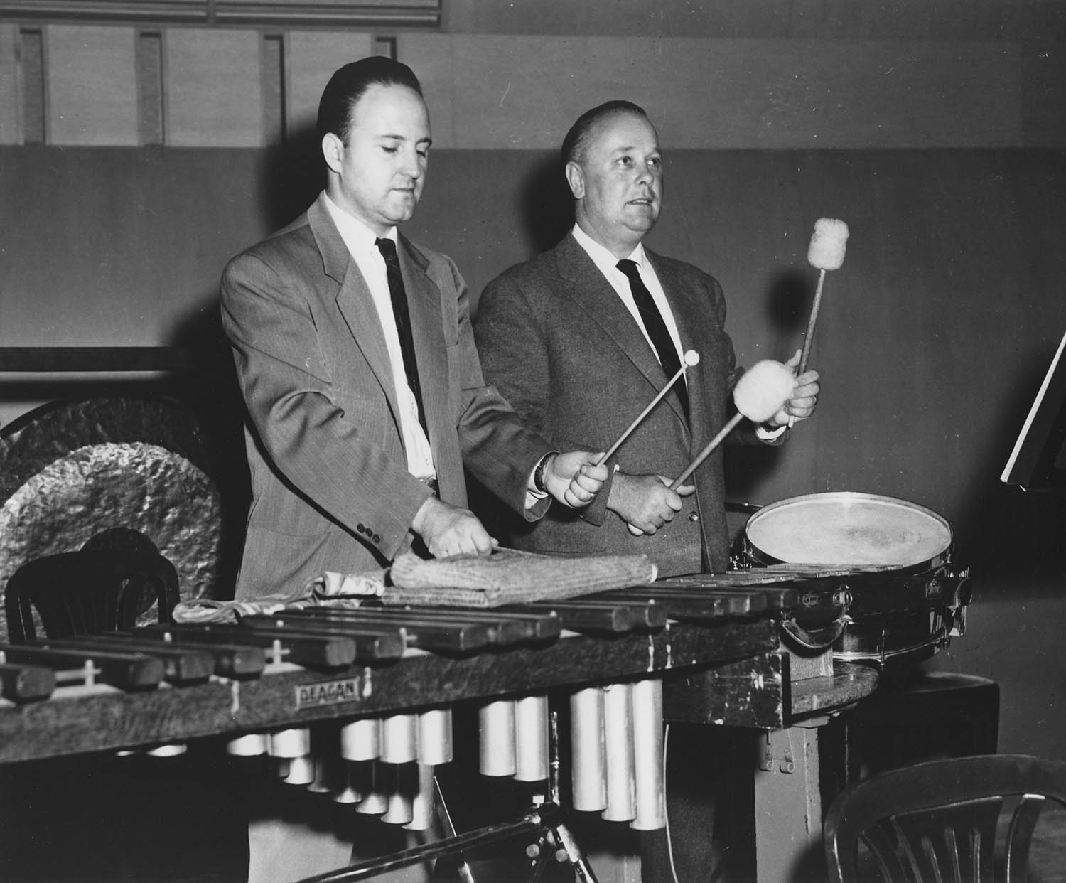 Program annotator Klaus George Roy (Left) and acoustical consultant Heinrich Keilholz (Right) conduct tests on reverberation times with percussion instruments on the renovated Severance Hall stage. Unknown photographer, 1958. 