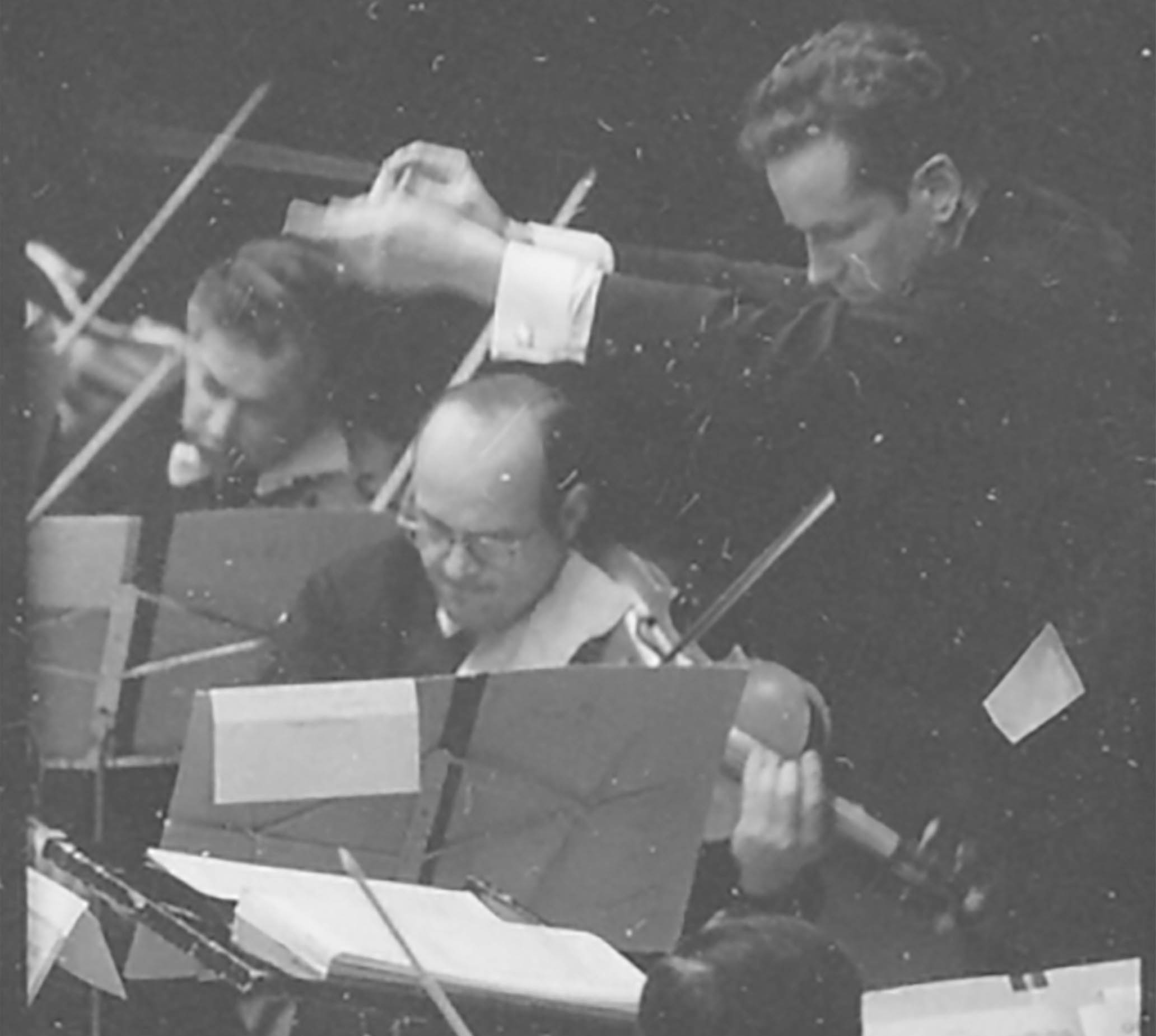 A youthful Louis Lane conducts the Orchestra. Everyone wears a serious, intense expression.t