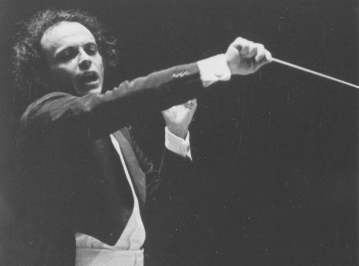 Maazel is conducting the Orchestra. His hair looks wild, and he is conducting aggressively. 
