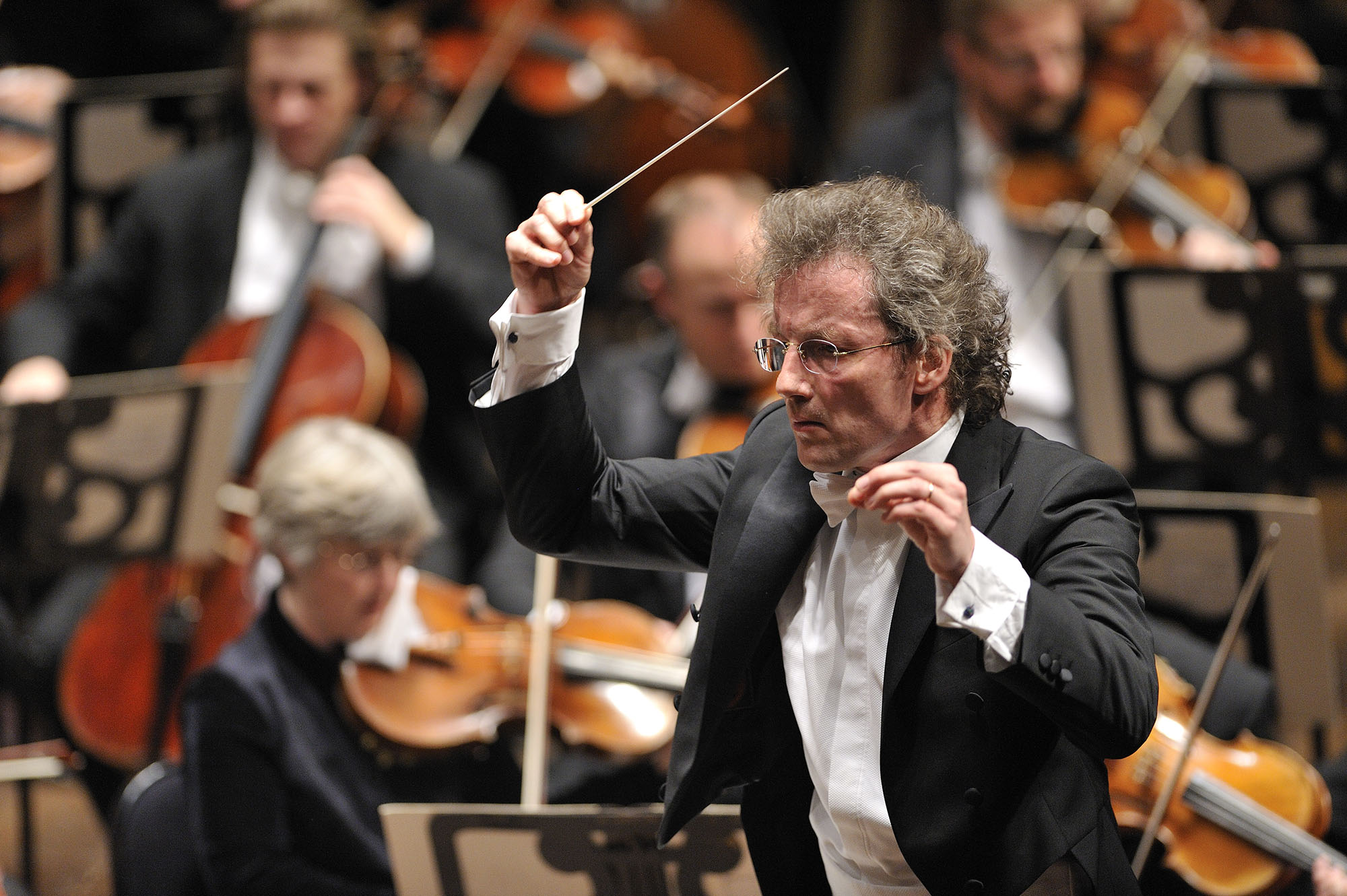 Franz is conducting the Orchestra with a serious expression on his face. 