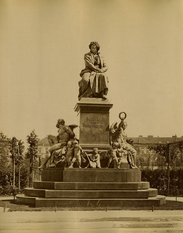 A statue of Beethoven. On his right is Prometheus, on his left is Nike, the goddess of victory. Small putti are at Beethoven’s feet.