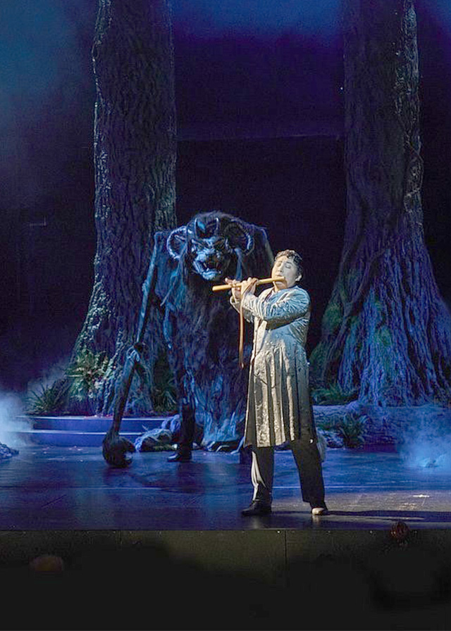 Man playing flute in a dark forest