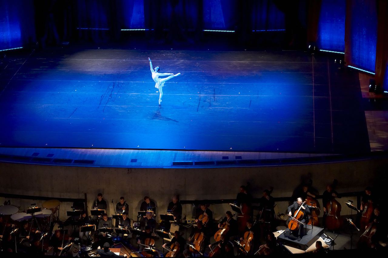 A ballerina from Joffrey Ballet graces the stage with the Orchestra visible in the pit below during a 2010 performance